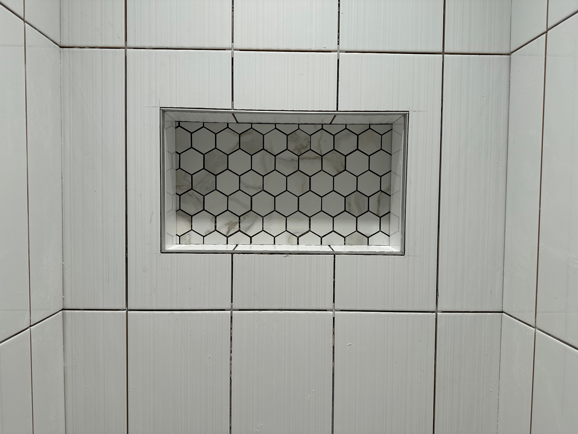 Subway tile shower wall with hexagon marble niche