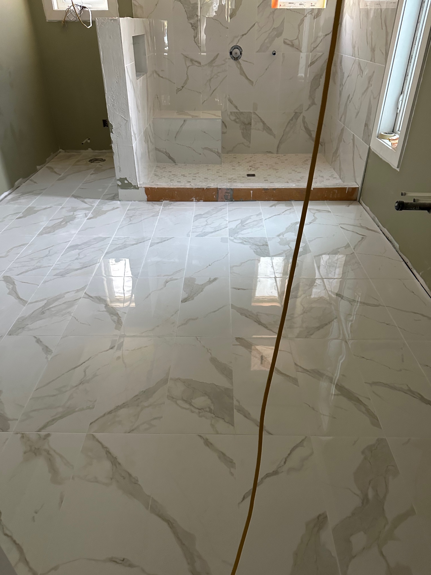 Polished marble-look porcelain bathroom floor with custom shower base
